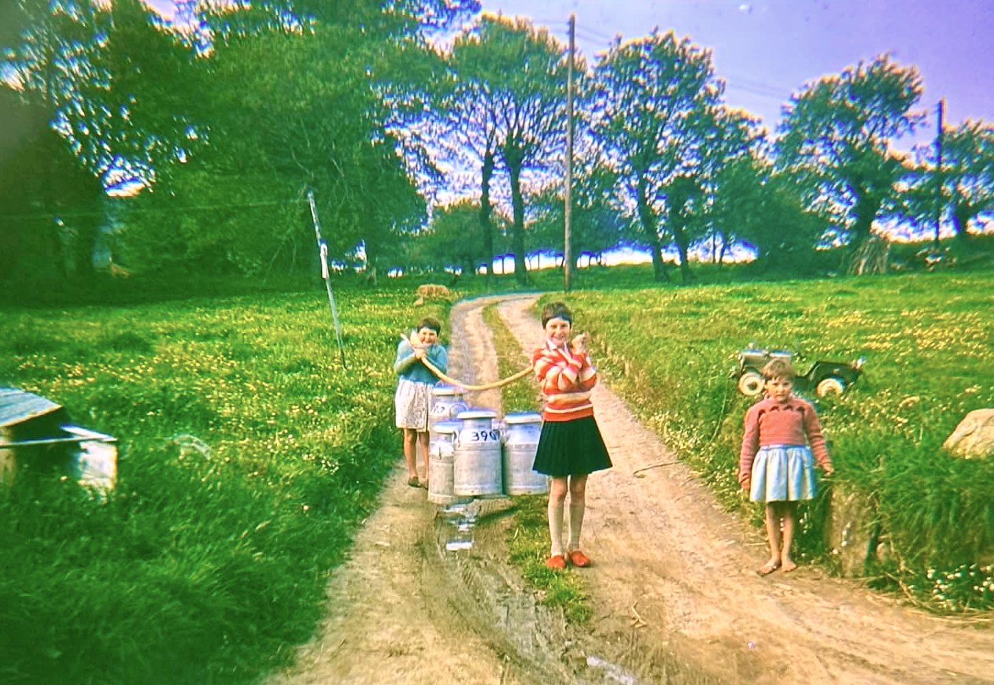 Jo and her sisters on the farm track at L'Hermitage in the 1960s, beside the milk cans left out for collection